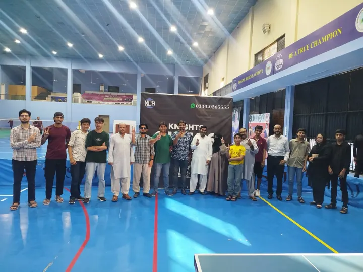 About twenty players and organisers lined up in front of the Knights Chess Academy banner, many holding up two fingers