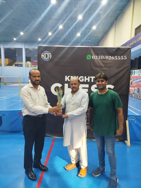 The runner-up, in a white shalwar kameez, receives a gold trophy marked Runner-up