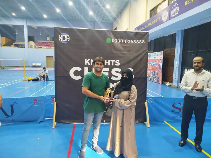 A woman player receives a special-prize trophy while an organiser applauds