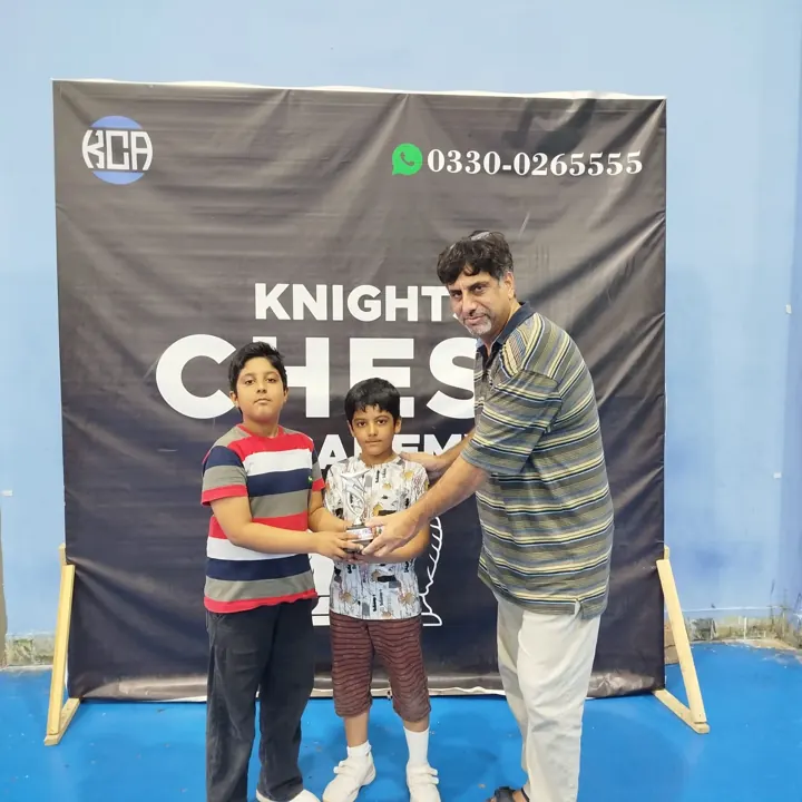 Two young boys hold a special-prize trophy together as an organiser hands it over